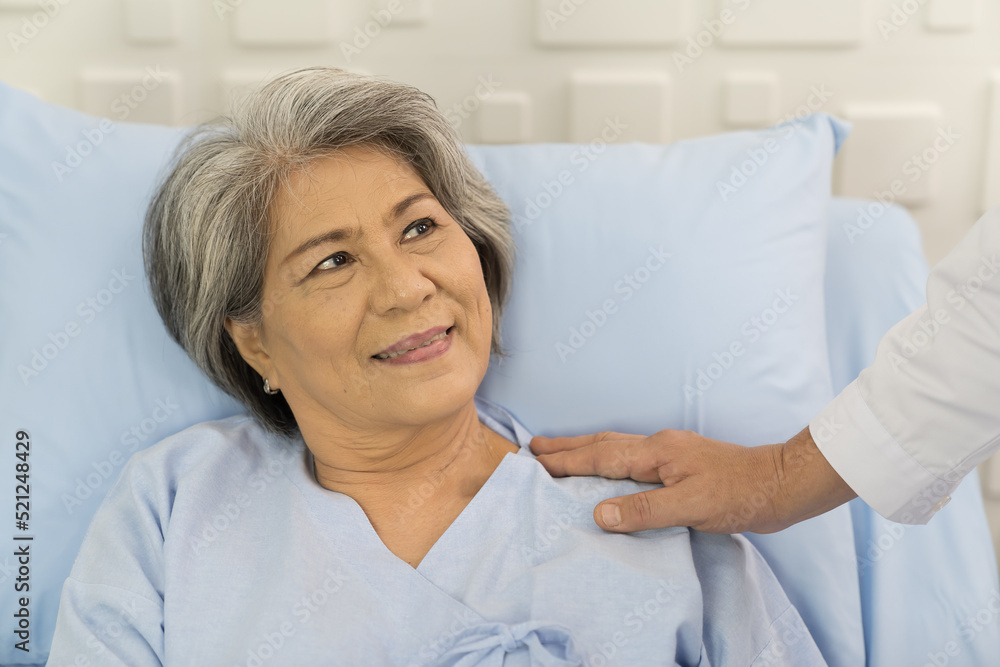 Fototapeta premium Closeup of hands of doctor and patient elderly woman. Hands of doctor touch on shoulder of elderly asian woman on bed at the hospital. People and health care concept