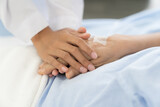 Closeup of hands of nurse and elderly woman. Hands of nurse holding hand of elderly woman on bed at the hospital. People and health care concept