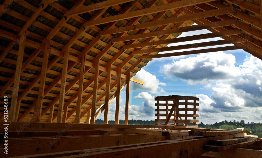 Fototapeta premium Construction of a brick and wooden roof house construction in progress