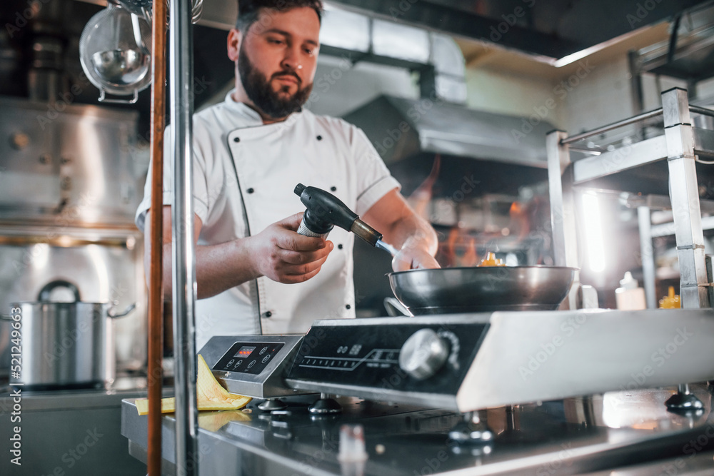 Food is on the weights. Flames in the plate. Professional chef preparing food in the kitchen Food is on the weights. Flames in the plate. Professional chef preparing food in the kitchen
