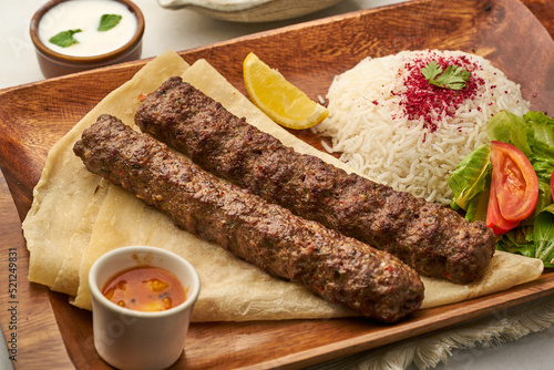 Photos Chelo Kebab with rice, lime, salad, tomato, raita and sauce served in a dish iso
