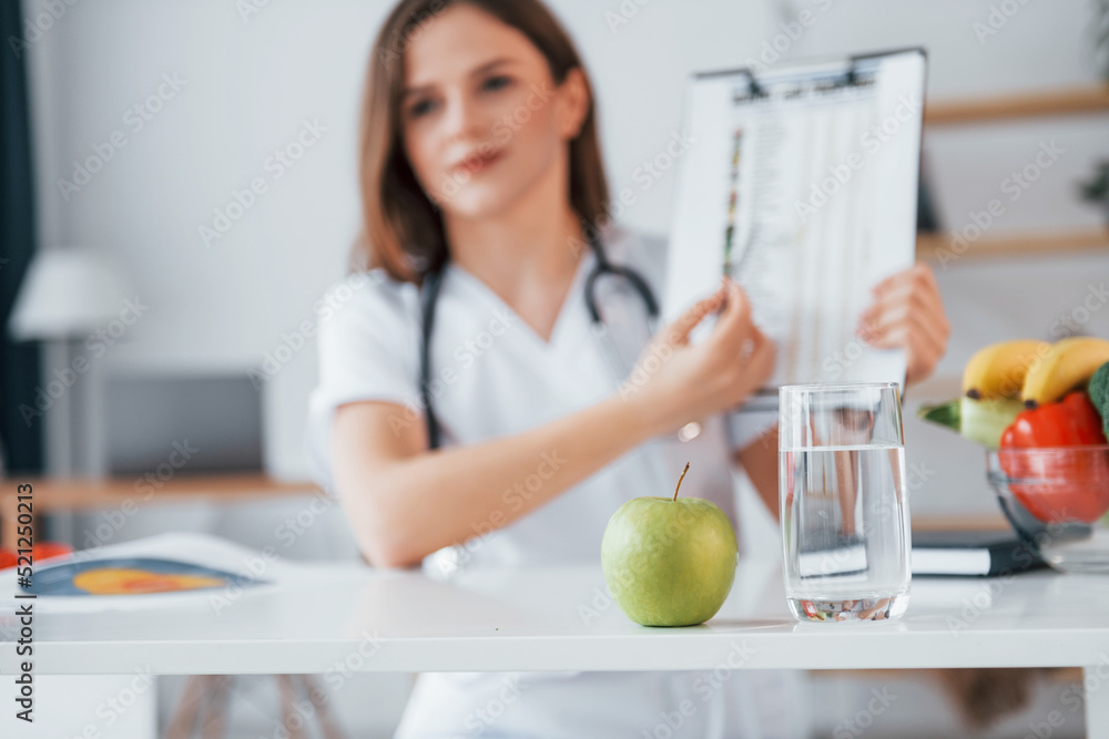 With document in hands. Professional medical worker in white coat is in the office With document in hands. Professional medical worker in white coat is in the office