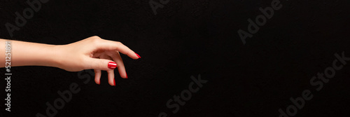 Stampa su tela Female hand with beautiful manicure - red nails on dark black background with copy space banner