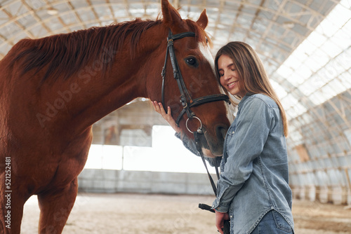 Young woman in jeans clothes is with horse on a stable © standret