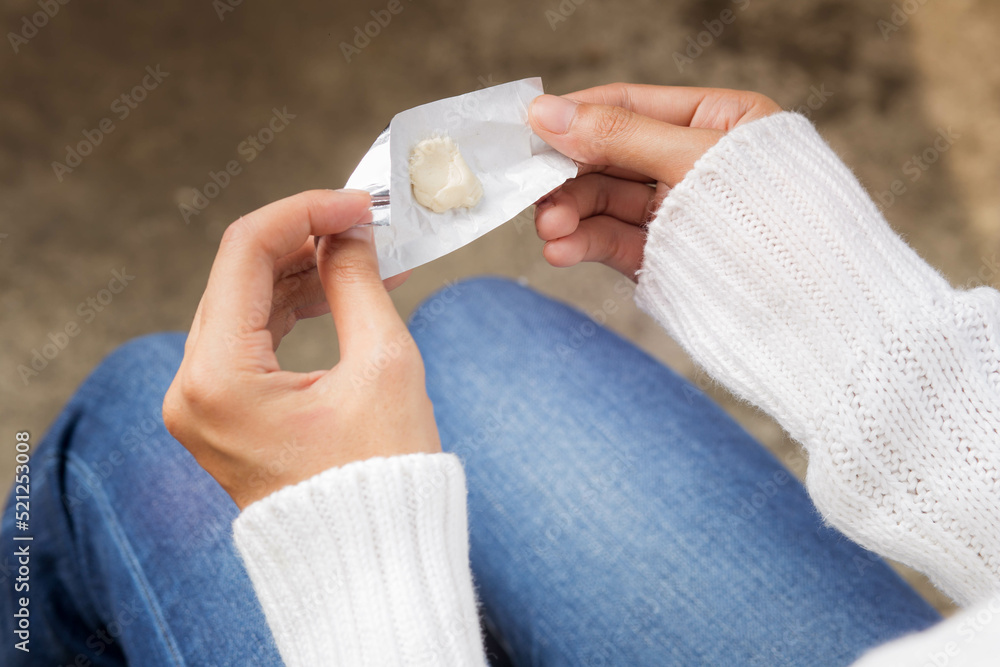 A woman wrapped a piece of chewing gum with wrapping paper before