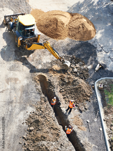 Excavator and workers digging trench