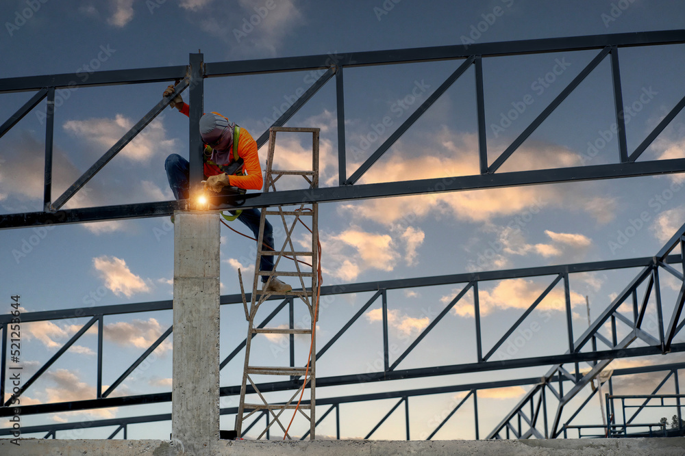 Fototapeta premium Welders wear safety belts and plastic helmets to weld steel structures.