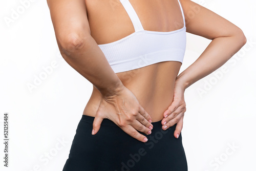 Cropped shot of a young woman holding her lower back with her hands isolated on a white background. Back pain. Sciatica, osteochondrosis, gallstone disease, pancreatitis. Sports injury photo