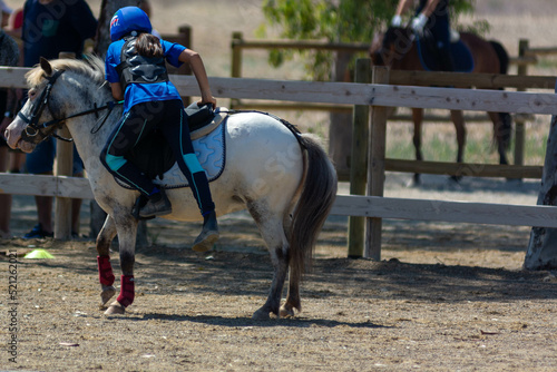 Little Girl that gets back in th saddle of a Pony during Pony competition at the Equestrian School