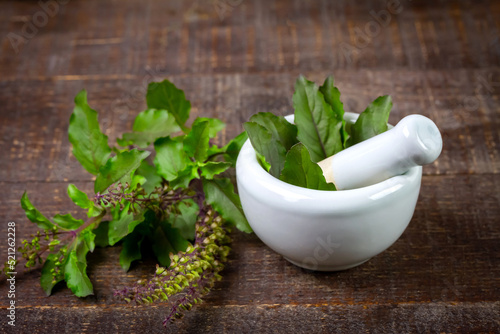 Tulsi or Holy basil leaf in mortar with pestle on rustic wooden table. Tulsi is used in ayurvedic medicine.