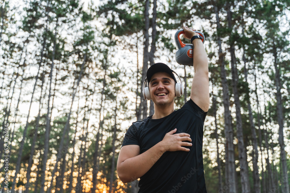 A young man training in the forest during the golden hour stretching and measuring pulse while enjoying nature