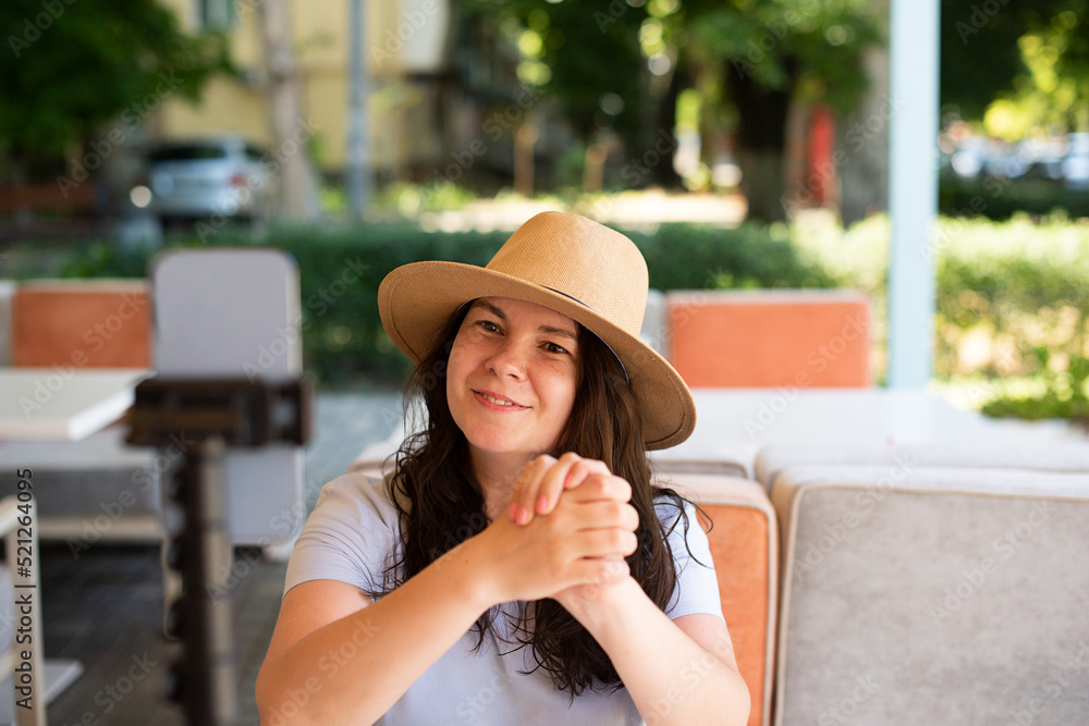 Attractive woman outside sitting with tripod and smartphone,making video call or providing online lesson.