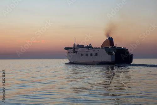 the ferry leaves the harbor at sunset on a warm summer evening © aigarsr