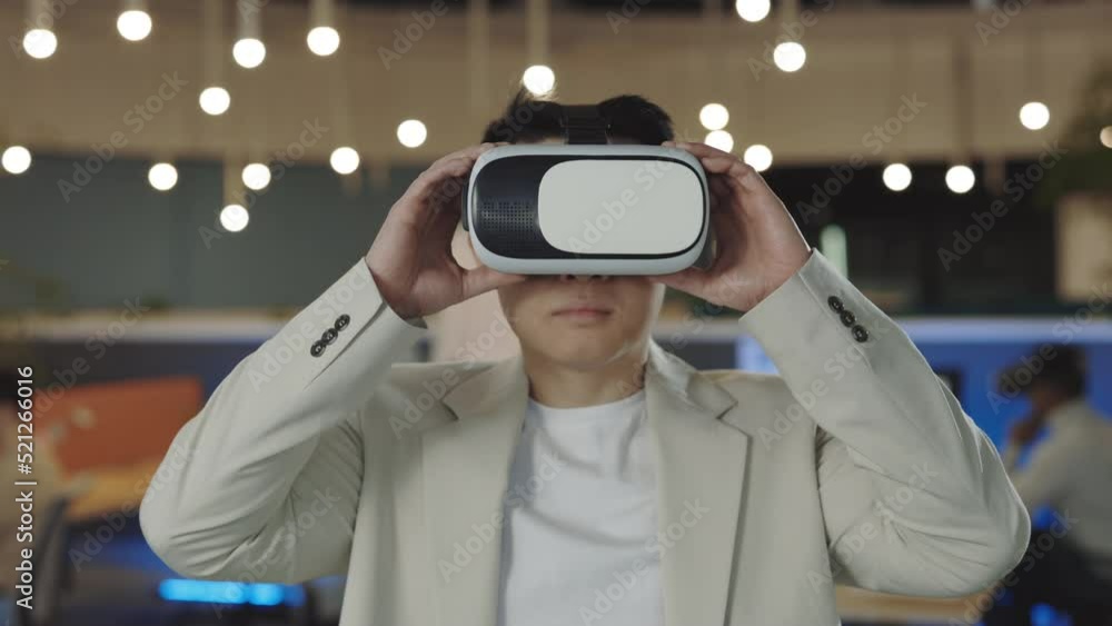 Office male worker wearing a VR headset, virtual reality concept. Portrait asian software developer standing in office room. It, business and new technologies concept Office male worker wearing a VR headset, virtual reality concept. Portrait asian software developer standing in office room. It, business and new technologies concept