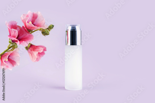 glass bottles for cosmetics and flowers on a purple background