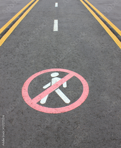 Road section with road markings regulating the movement of pedestrians. No pedestrians Allowed. Circular traffic sign. White man Symbol Painted over gray Asphalt. Signs drawn on the pavement © Albina