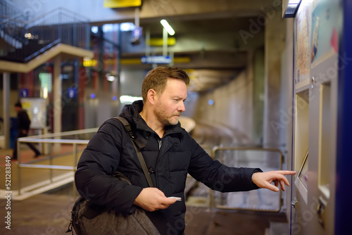 Mature man buys ticket for the subway or train using ticket vending machine at the station © Maria Sbytova