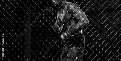 Black and white image of a man in a boxing cage. The concept of sports, Muay Thai, martial arts.