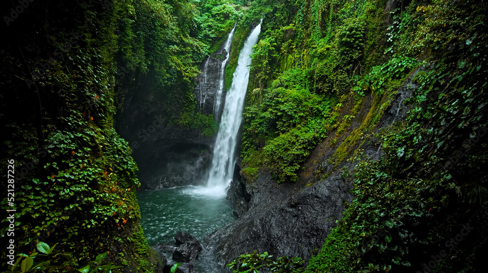 waterfall with rocks among tropical jungle with green plants and trees and water falling down waterfall with rocks among tropical jungle with green plants and trees and water falling down