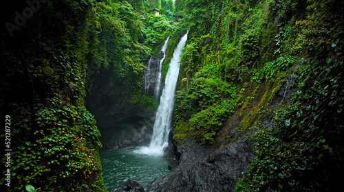 waterfall with rocks among tropical jungle with green plants and trees and water falling down