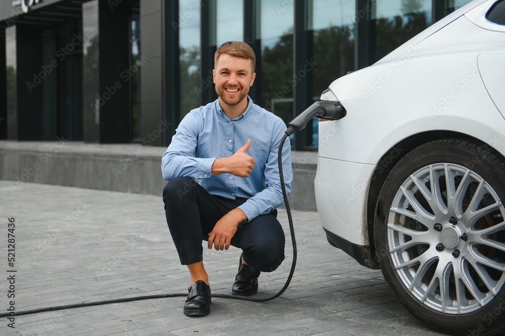 Man charges an electric car at the charging station
