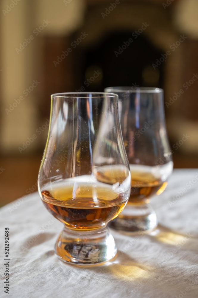 Two glasses of scotch whiskey with view on fireplace in old house on background, Edinburgh whisky tasting tour, Scotland Two glasses of scotch whiskey with view on fireplace in old house on background, Edinburgh whisky tasting tour, Scotland