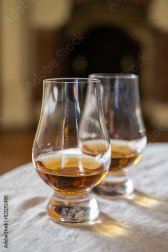 Two glasses of scotch whiskey with view on fireplace in old house on background, Edinburgh whisky tasting tour, Scotland
