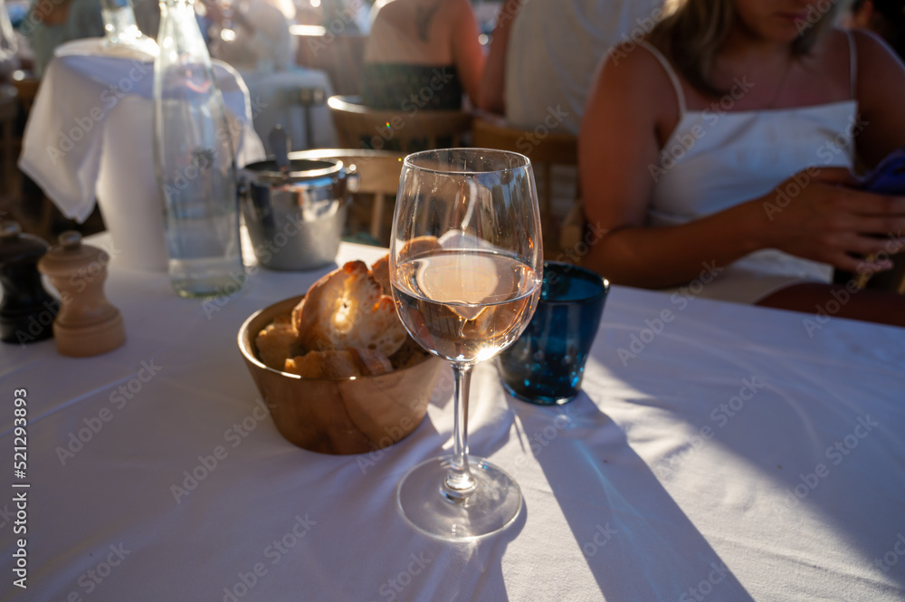 Dinner at sunset in French restaurant with cold dry rose wine in Port Grimaud, summer vacation on French Riviera, France
