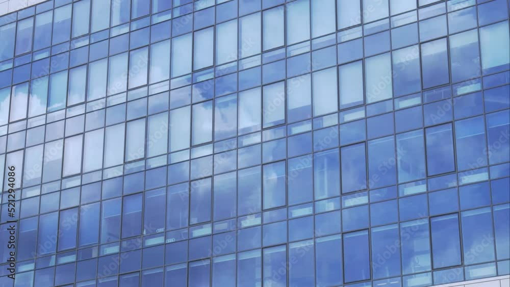 Modern office building facade. Tall business center with a glass facade. Construction of a glass facade structure. The glare of the sun on the glass wall of a skyscraper Modern office building facade. Tall business center with a glass facade. Construction of a glass facade structure. The glare of the sun on the glass wall of a skyscraper