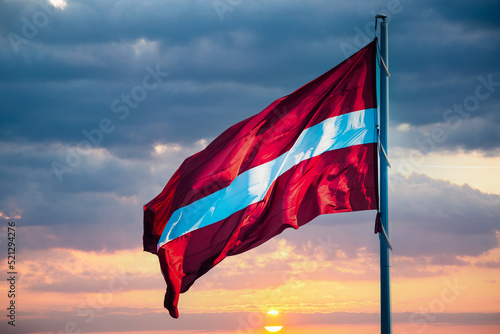 Flag of the Republic of Latvia. Latvian flag waving in the wind against the beautiful sunset photo