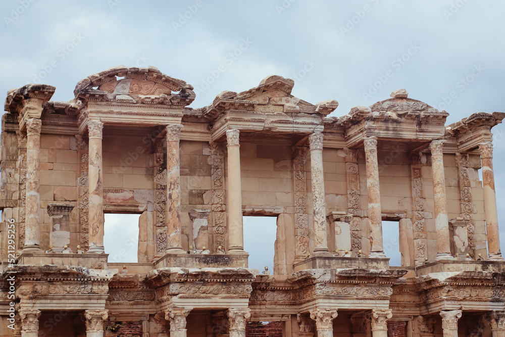 Close up of upper front side of the Library of Celsus with clouds on the sky
