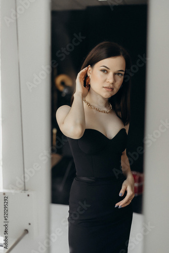 A girl in a black dress stands on a white background