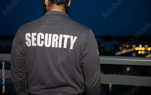 A rear view of a security guard walking through the street of the big city at night.