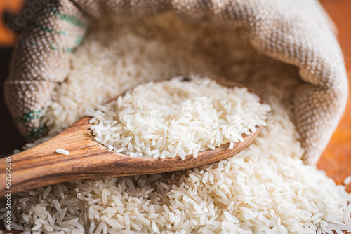 Uncooked white rice on wooden spoon.