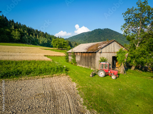 Czerwony traktor przed stodołą w górach