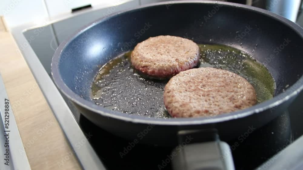 Frozen burger patties burger meat sizzling in hot pan with fat and oil