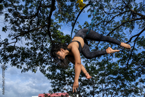 Young Latin American woman in the open-air aerial hoop