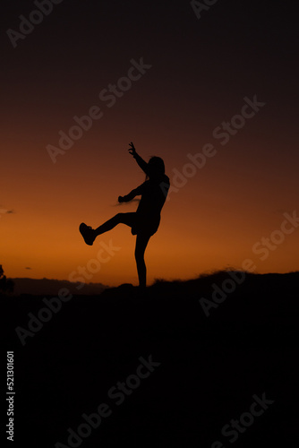 silueta de mujer saltando en un atardecer. Concepto de personas y estilos de vida. © artrolopzimages