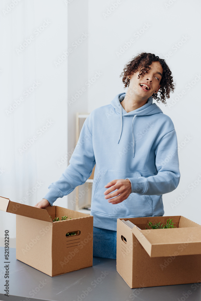 guy with curly hair cardboard boxes in the room unpacking Lifestyle guy with curly hair cardboard boxes in the room unpacking Lifestyle