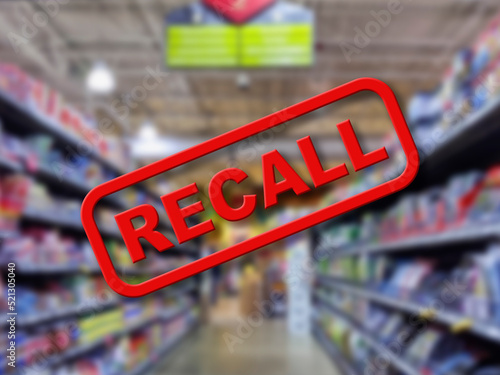 Blurry interior of a grocery store aisle behind large red Recall text photo