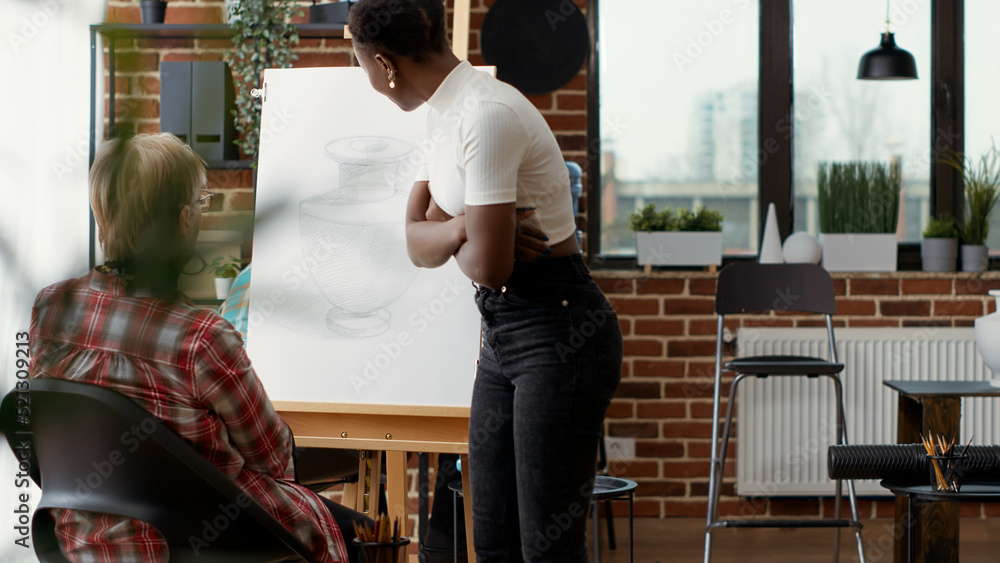 Art teacher training senior woman to draw artwork in art class program