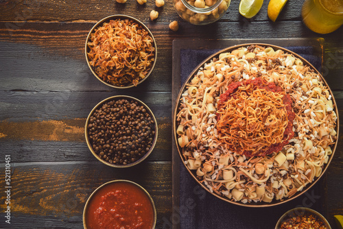 Arabic cuisine; Traditional Egyptian food:Delicious Kushary or Koushari of rice,pasta,chickpeas,lentils,crispy fried onions,fresh lemon and tomato garlic sauce on a plate.Top view with copy space.