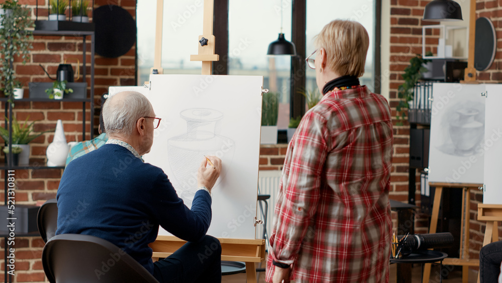 Artist supervising senior man drawing on canvas in art class, attending ...