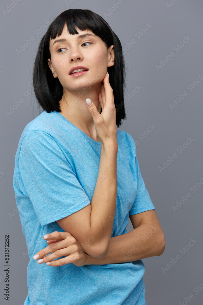 a peaceful woman stands against a dark background in a blue T-shirt leaning her palm against her cheek calmly looking away holding her hand a peaceful woman stands against a dark background in a blue T-shirt leaning her palm against her cheek calmly looking away holding her hand