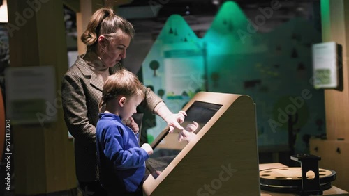 child education and development, caring male parent helping his son through modern learning method on touch screen in museum