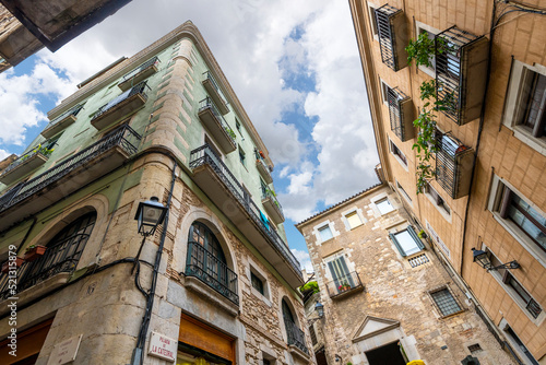 Colorful and historic buildings seen from below at the Pujada de Catedral, the plaza at the base of the steps to the Cathedral of Girona, in the town of Girona, Spain. photo