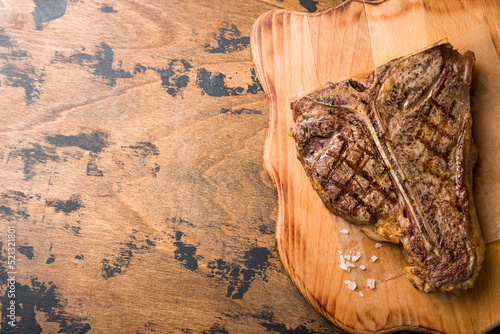 Steak T Bone, tibon steak, steak on bone on wooden table top view with copy space for text photo