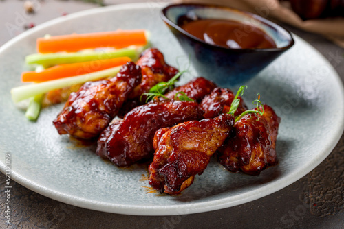 chicken wings in barbecue sauce on plate macro close up on brown stone table