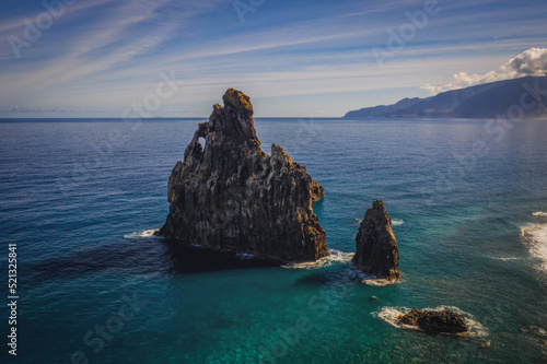 View of the Ilheus da Ribeira da Janela rock islets under a clear blue sky. The rocks form a famous landmark on the northern shore of the island of Madeira, Portugal. Aerial drone shot, october 2021