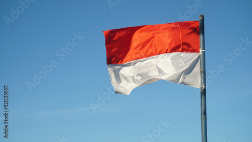 Red and white flag fluttering in the wind with blue sky Background